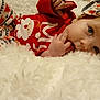 baby, infant, child, pajamas, red_clothing, white_blanket, headband, hand, face, eyes, lying_down, cute, holiday_theme, soft_texture, indoor, portrait, closeup, skin, fingers, comfort