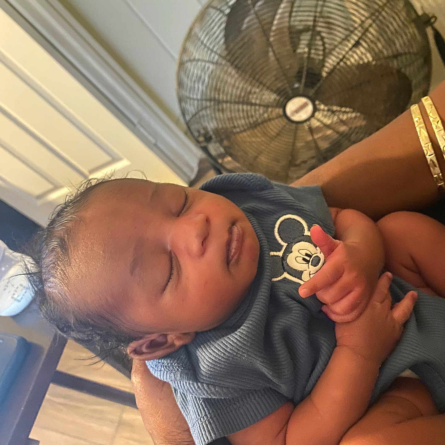Kyzir is registered to the contest to win money with this photo: baby, sleeping, infant, person, hand, clothing, mickey_mouse, fan, arm, indoor, floor, wood, skin, hair, cute, peaceful, child, holding, portrait, relaxing