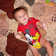 Sebastian joined the competition — help win amazing prizes! baby, bed, bedspread, cartoon_character, child, eyes, face, hair, happy, indoor, infant, lying_down, mickey_mouse, onesie, pluto, portrait, red_clothing, smiling, thumbs_up, toy