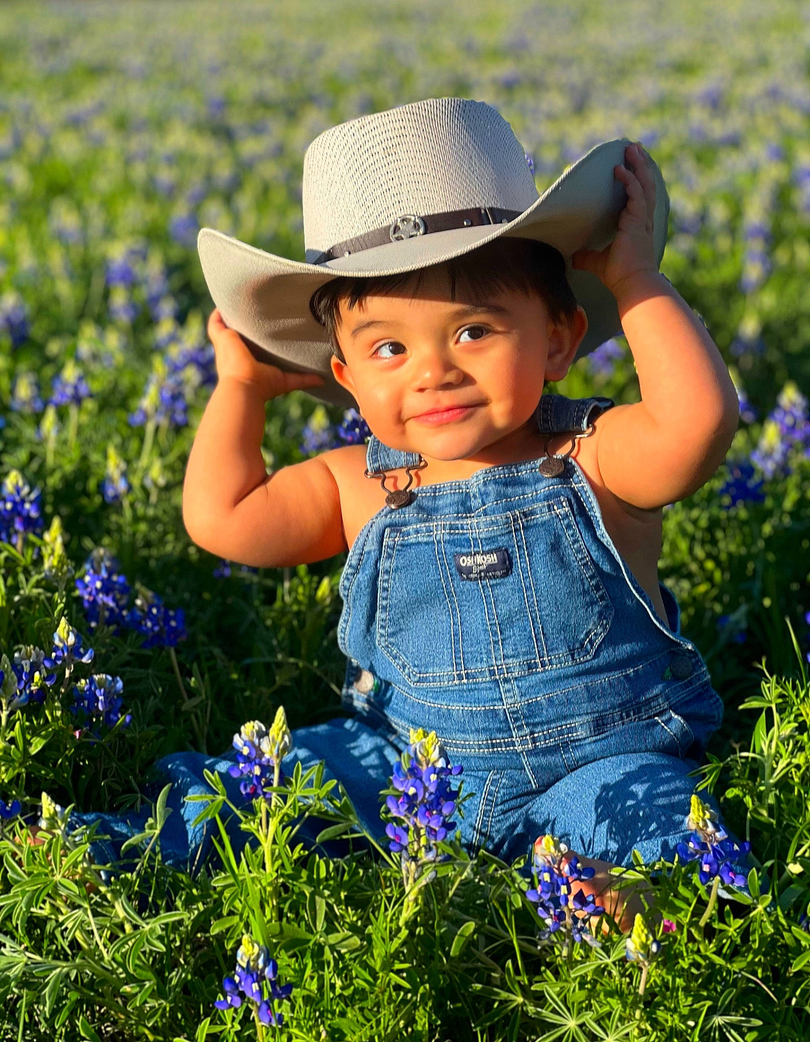 Jaxson is registered to the contest to win money with this photo: agriculture, baby_toddler_clothing, blue, face, flower, grass, grassland, groundcover, happy, hat, iris, joy, natural_landscape, people_in_nature, person, petal, photograph, plant, smile, summer