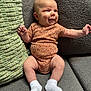 Ryker is registered to the contest to win money with this photo: baby, infant, smiling, onesie, white_socks, couch, green_cushion, gray_cushion, textured_fabric, happy, seated, indoor, child, cute, portrait, small_hands, small_feet, plush, cozy, relaxed