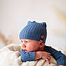 baby, infant, blue_hat, knit_hat, blanket, basket, cozy, cute, resting, soft_texture, child, portrait, side_view, warm_clothing, indoor, newborn, person, expression, hand, face