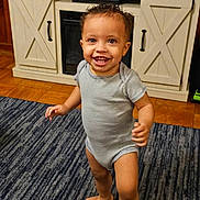 Mathias joined the competition — help win amazing prizes! toddler, child, smiling, indoor, carpet, striped_onesie, barefoot, wooden_floor, cabinet, furniture, curly_hair, happy, person, standing, home, living_room, baby, cute, portrait, young_child