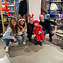Marley participe au concours pour gagner de l'argent avec cette photo : group, people, child, toddler, adult, holiday, festive, clothing_store, mannequin, red_coat, hat, glasses, smile, jeans, sneakers, sweater, floor, table, jacket, indoor