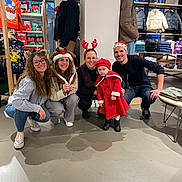 Marley a rejoint le concours — aidez-le/la à gagner de superbes lots ! group, holiday, festive, child, toddler, red_coat, hat, reindeer_ears, santa_hat, smiling, glasses, store, clothing_rack, winter_jacket, shopping, indoor, people, floor, casual, joyful