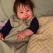 Adaline joined the competition — help win amazing prizes! baby, smiling, sleeping_bag, pillow, bed, indoor, clothing, child, face, happy, infant, person, portrait, textile, cozy, toddler, blanket, cute, furniture, relaxing