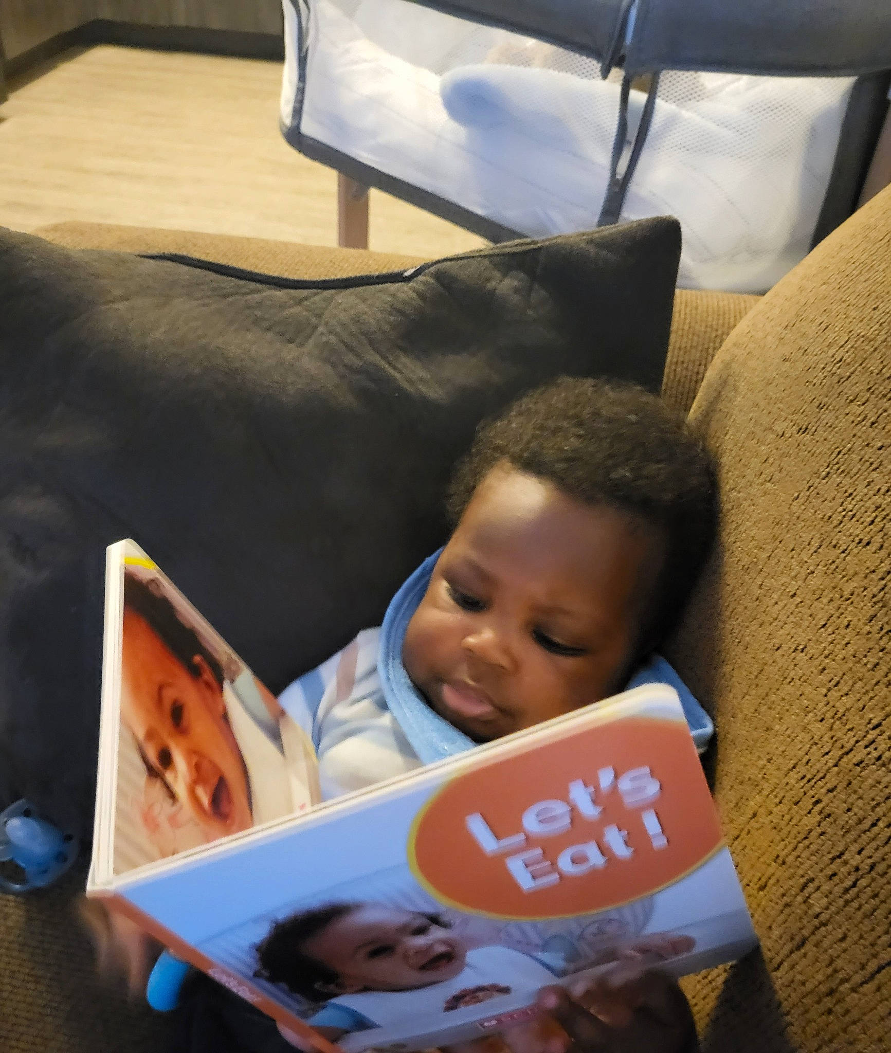Marck Messiah is registered to the contest to win money with this photo: baby, child, comfort, couch, flooring, fun, happy, lap, linens, living_room, person, reading, room, sitting, smile, throw_pillow, toddler, wood