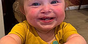 Elsie is registered to the contest to win money with this photo: toddler, child, smiling, happy, face, hands, yellow_shirt, bow, indoor, table, chair, person, cute, baby, skin, expression, cheeks, eyes, hair, clothing