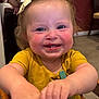 toddler, child, smiling, happy, face, hands, yellow_shirt, bow, indoor, table, chair, person, cute, baby, skin, expression, cheeks, eyes, hair, clothing