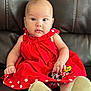 baby, child, red_dress, polka_dots, minnie_mouse, sitting, leather_couch, white_shoes, curious, portrait, indoor, cute, infant, clothing, footwear, face, young, person, smiling, closeup
