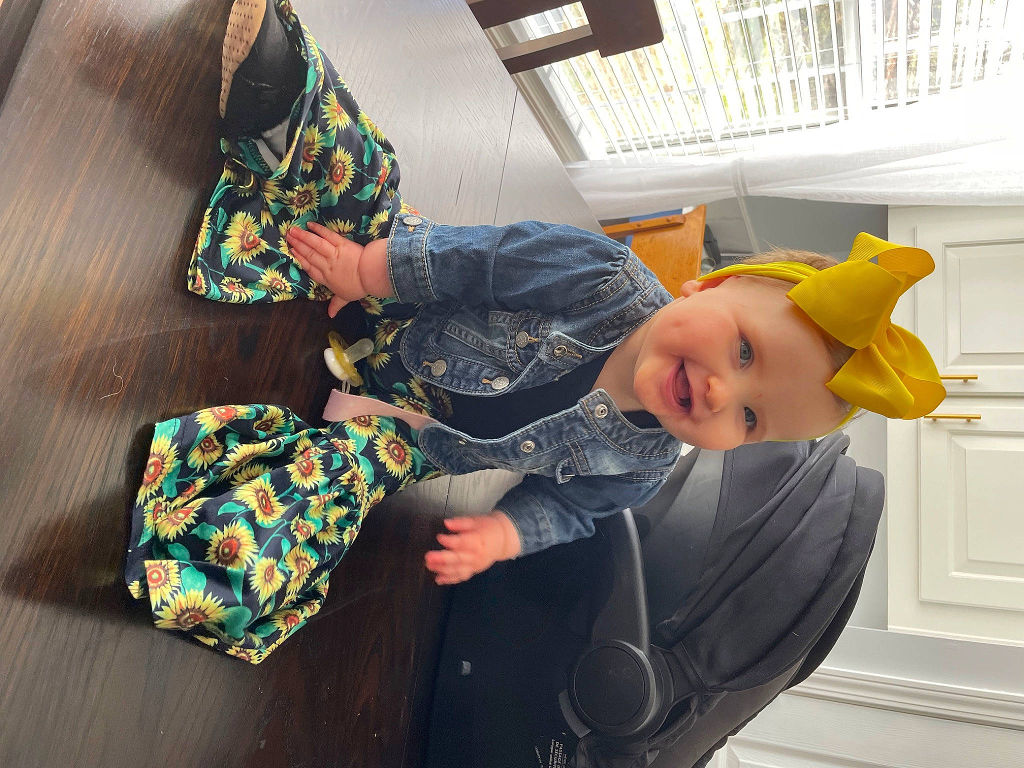 Callie is registered to the contest to win money with this photo: baby, baby_products, baby_toddler_clothing, child, comfort, fashion_accessory, flooring, happy, hat, headgear, headwear, linens, outerwear, pattern, person, product, room, sitting, sleeve, t_shirt