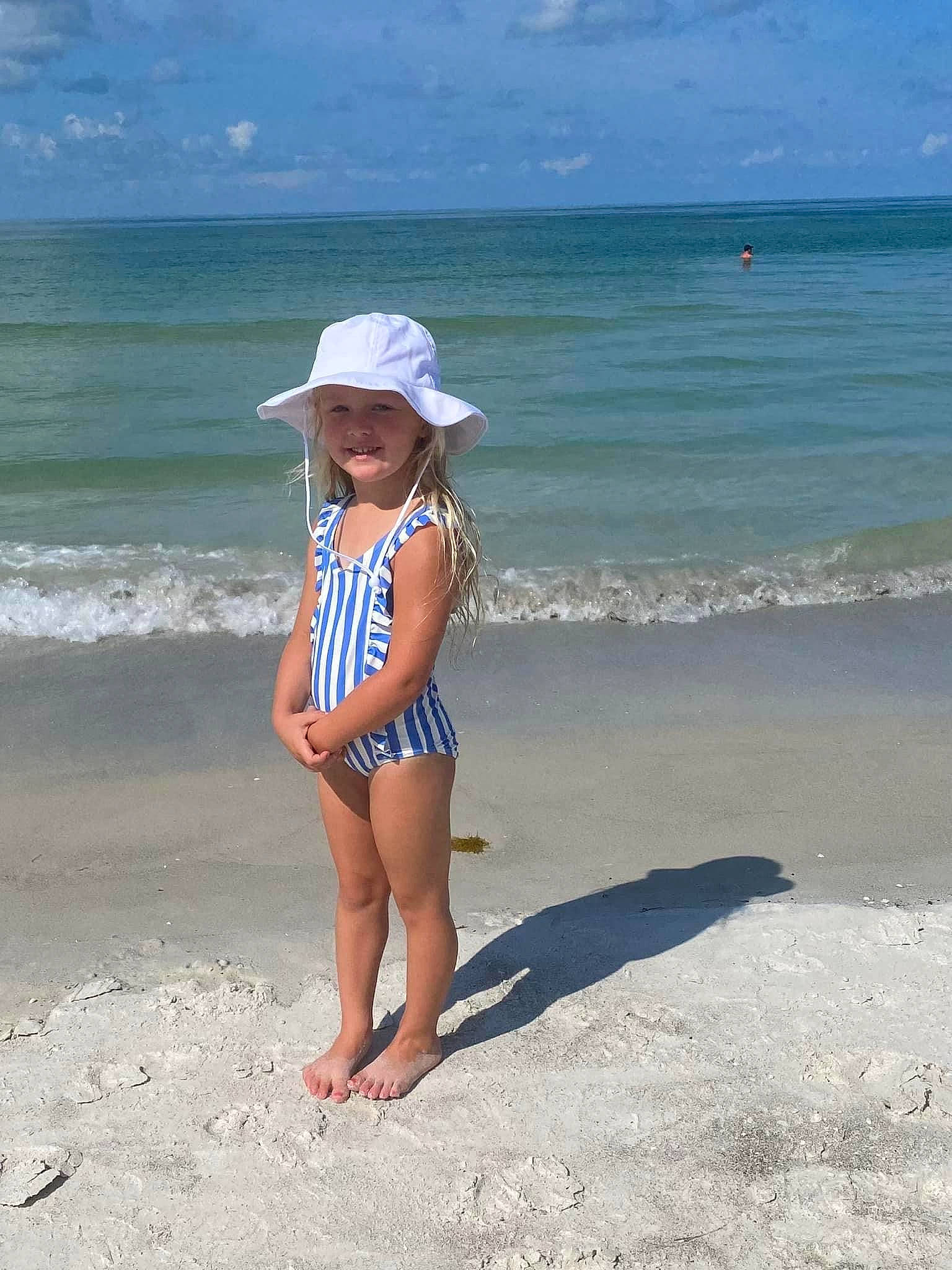 Breckyn is registered to the contest to win money with this photo: aqua, azure, beach, clothing, cloud, fun, happy, hat, headwear, horizon, joy, leisure, people_on_beach, person, sand, sky, smile, sun_hat, thigh, toddler