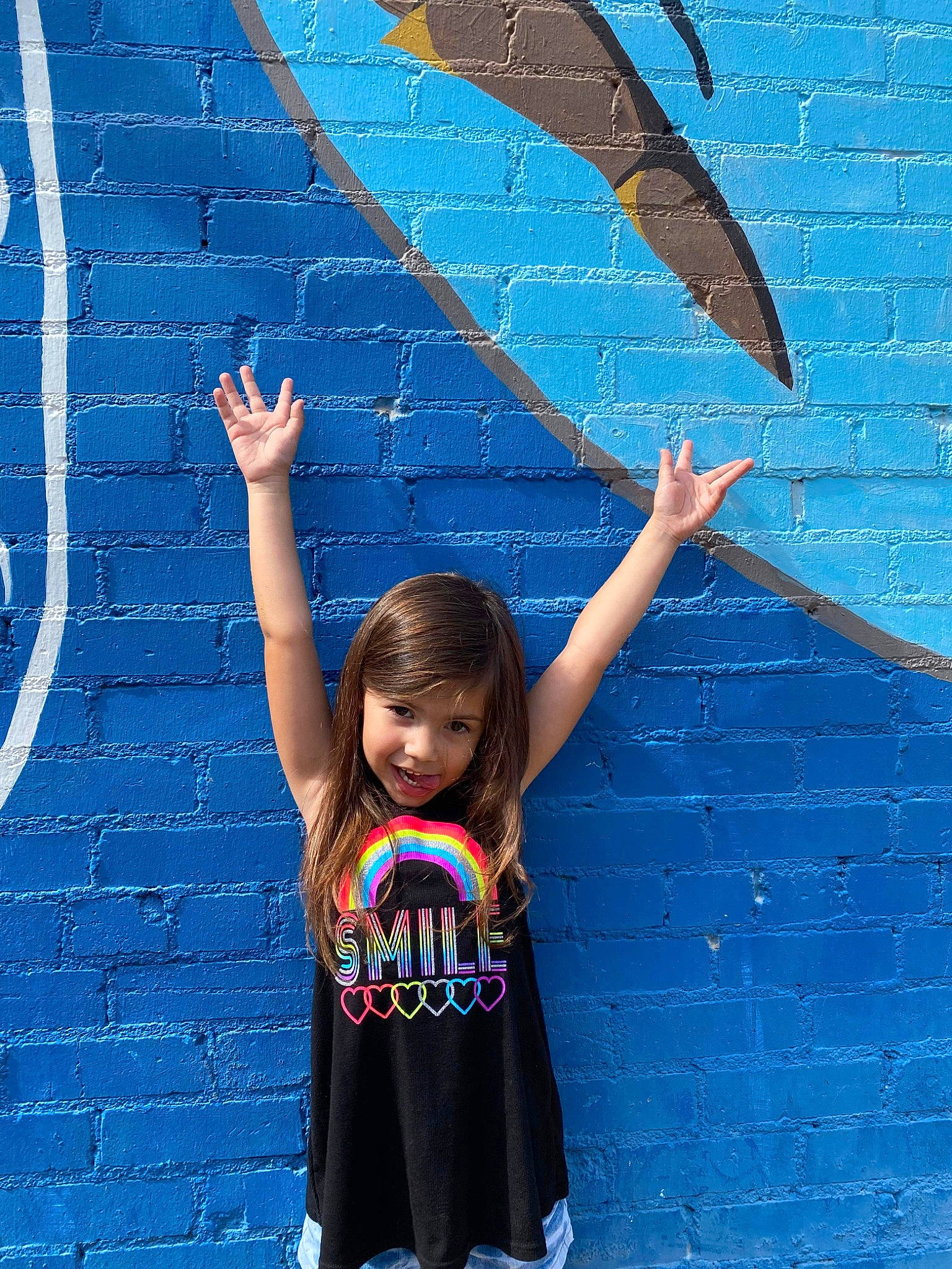 Annabell is registered to the contest to win money with this photo: azure, blue, brick, electric_blue, fun, gesture, happy, joy, leisure, mural, pattern, person, photograph, recreation, red, snapshot, standing, t_shirt, toddler, visual_arts