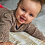baby, child, smiling, happy, face, blue_eyes, sweater, patterned_clothing, hand, cushion, indoor, portrait, cute, toddler, skin, head, fingers, wooden_beams, soft_texture, closeup