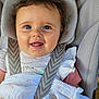 baby, infant, smiling, car_seat, seatbelt, blanket, white_clothing, child, happy, face, headrest, fabric, texture, closeup, cute, person, indoors, soft_light, skin, small_child