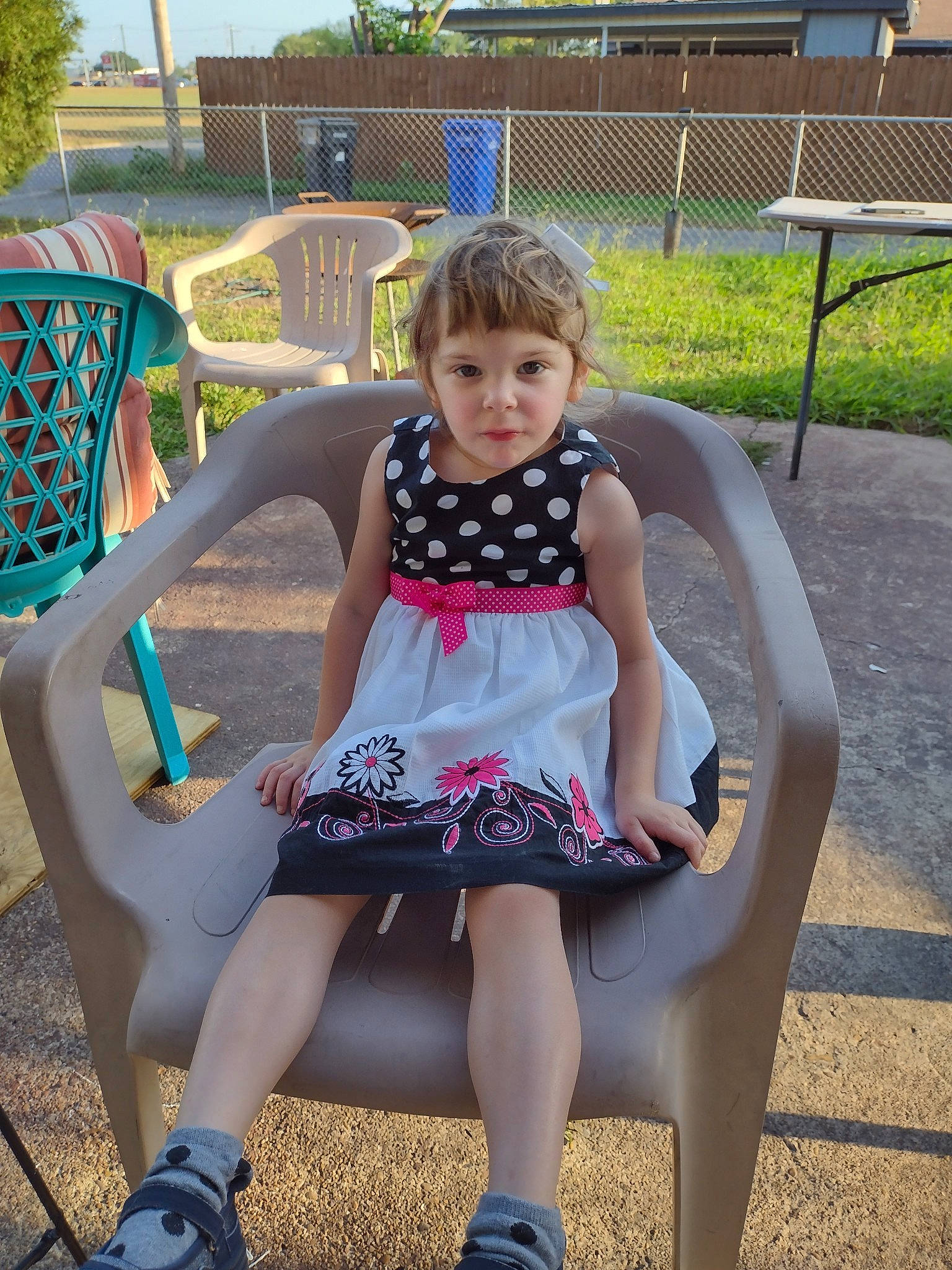 Sadie is registered to the contest to win money with this photo: baby_toddler_clothing, chair, child, dress, fun, grass, green, happy, human_body, human_leg, leg, leisure, outdoor_bench, outdoor_furniture, pattern, person, pink, plant, summer, thigh