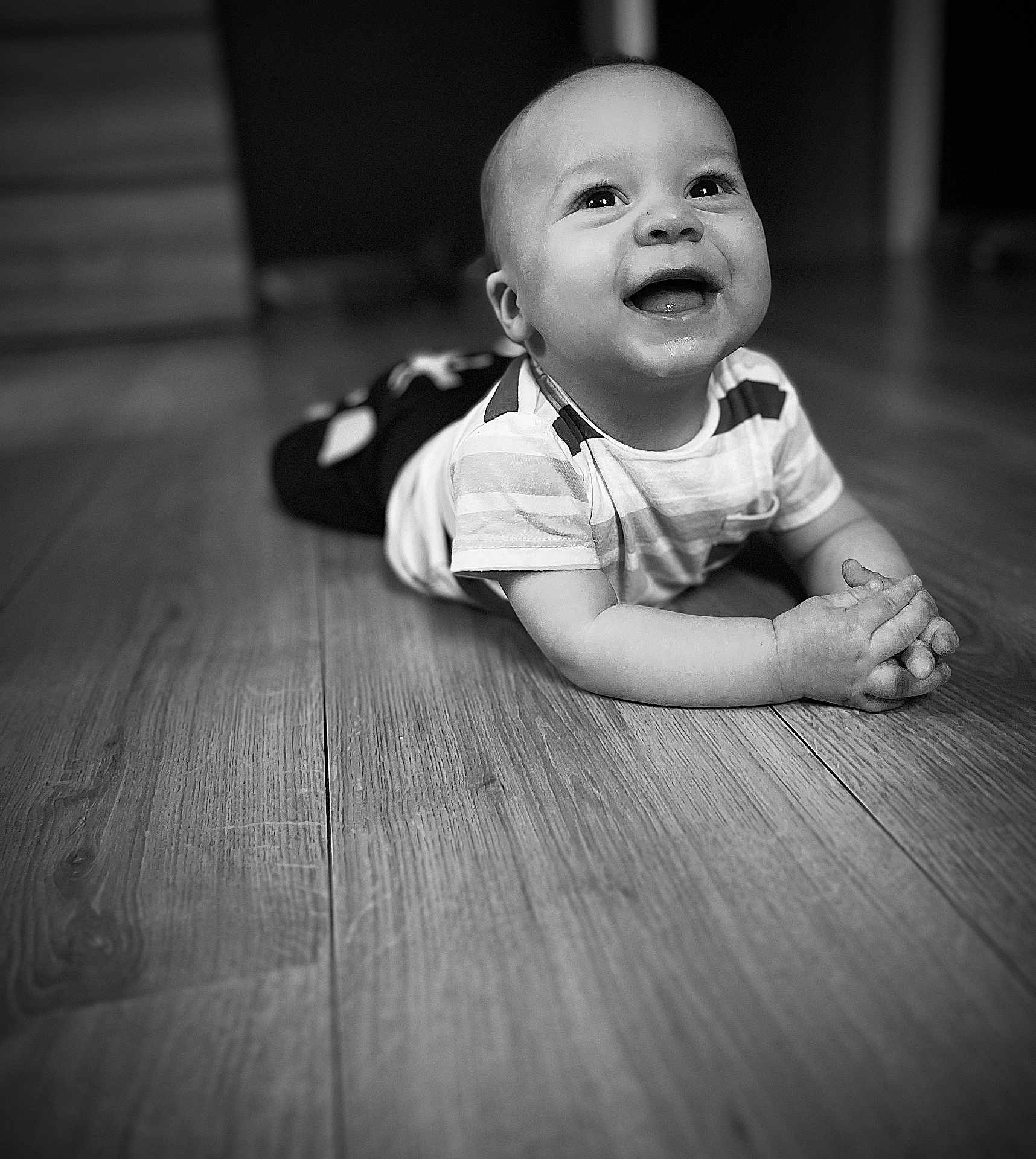 Tino participe au concours pour gagner de l'argent avec cette photo : baby, child, smiling, black_and_white, wooden_floor, toddler, happy, portrait, indoor, crawling, clothing, person, hands, face, eyes, expression, flooring, infant, cute, young