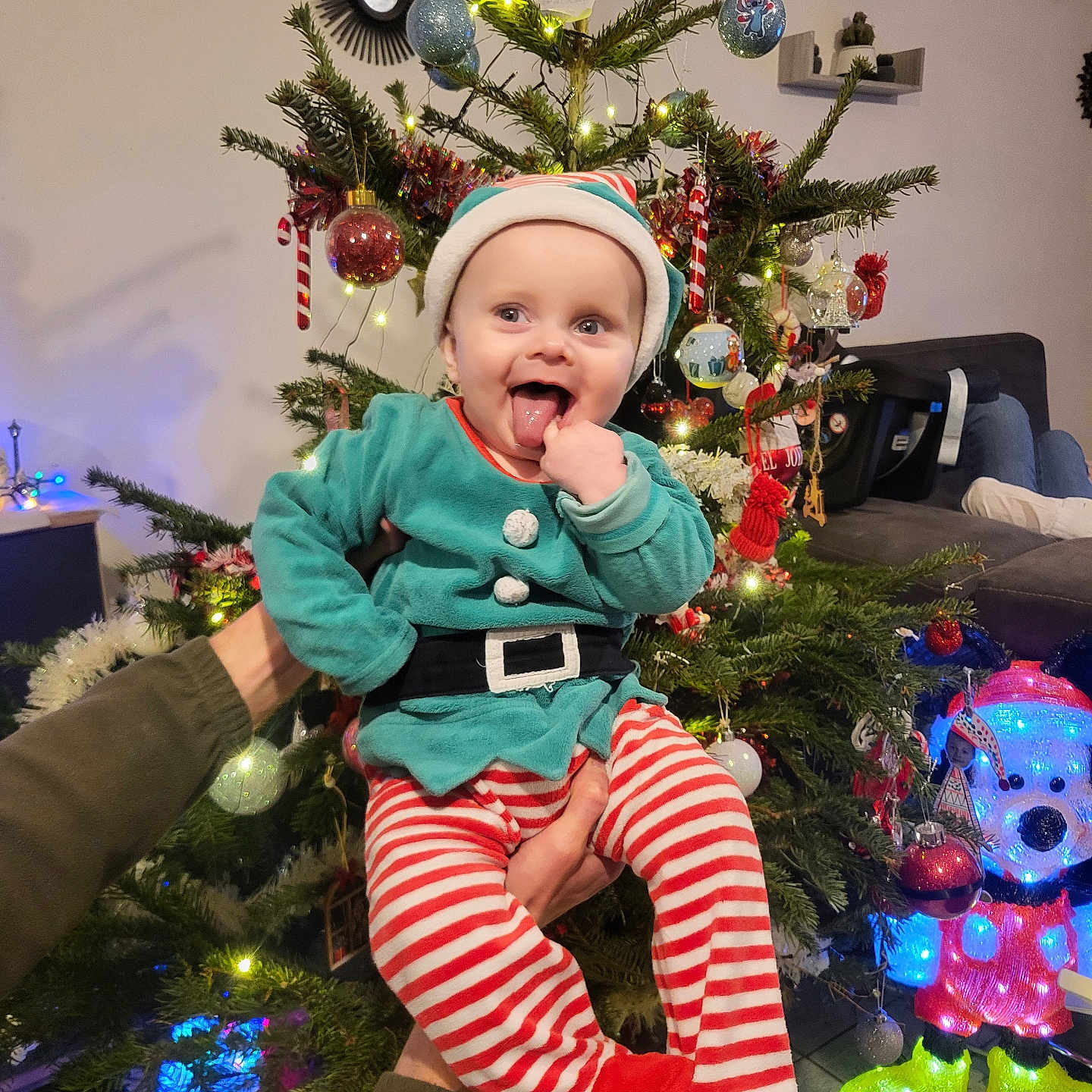 Néo participe au concours pour gagner de l'argent avec cette photo : baby, celebration, cheerful, child, christmas_tree, decorations, elf_costume, festive_clothing, holding_hands, holiday, home, indoor, lights, ornaments, person, red_booties, seasonal, smiling, striped_pants, tongue_out