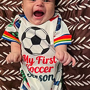 Wesley joined the competition — help win amazing prizes! baby, infant, smiling, happy, soccer, sportswear, clothing, patterned_blanket, lying_down, cute, cheerful, child, portrait, colorful, onesie, fun, joyful, young_child, expression, celebration