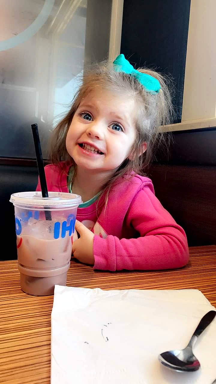 Athena Garcia is registered to the contest to win money with this photo: chair, child, couch, drink, drinking, drinking_straw, drinkware, event, face, fun, happy, joy, person, play, room, sitting, smile, sweetness, table, tableware