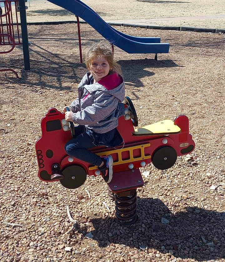 Athena Garcia is registered to the contest to win money with this photo: baby, city, fun, grass, joy, leisure, outdoor_furniture, outdoor_play_equipment, person, play, playground, recreation, riding_toy, shade, sitting, smile, soil, tire, toddler, toy_vehicle