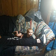 Malachi Brown joined the competition — help win amazing prizes! baby, couch, person, shoe, sneaker, wood_paneling, carpet, clothing, indoor, light, sunlight, remote_control, fabric, diapers, plastic, bubble_wrap, floor, leg, pattern, room