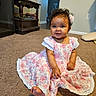 baby, child, girl, curly_hair, flower_clip, pink_dress, lace, carpet, indoor, smiling, sitting, furniture, wooden_table, door, home, floor, cute, portrait, person, happy