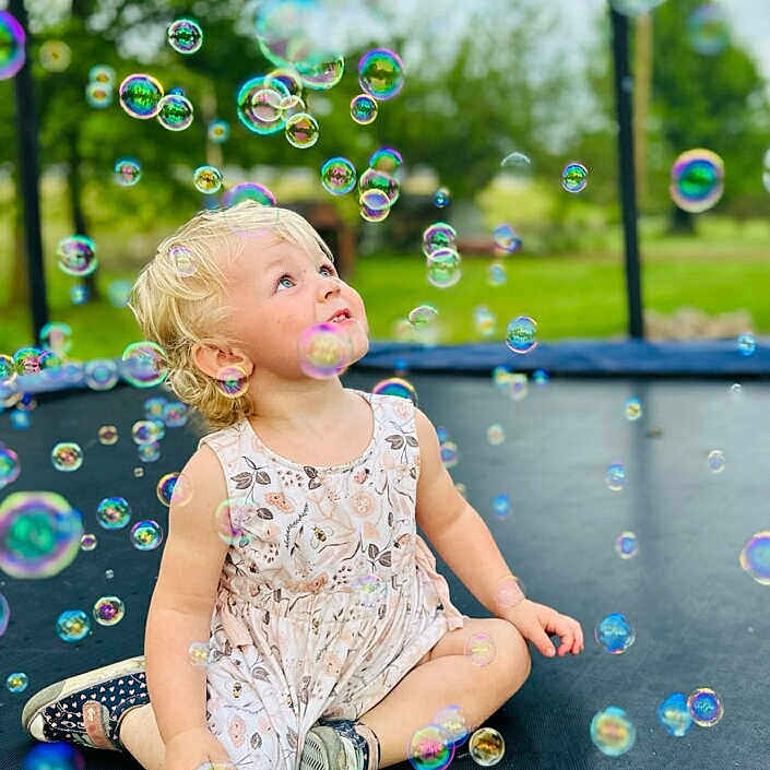 Kimber Liberty is registered to the contest to win money with this photo: baby, blonde, clothing, dress, face, footwear, grass, hair, head, nature, outdoorplayarea, outdoors, person, photography, plant, playarea, portrait, shoe, sitting, summer