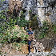 Vico a rejoint le concours — aidez-le/la à gagner de superbes lots ! man, dog, husky, rock, cliff, nature, outdoor, leash, hiking, smiling, greenery, tree, jacket, glasses, adventure, trail, mountain, wildlife, landscape, pet