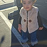 car, casual, child, clothing, curly_hair, cute, daylight, fashion, jeans, outdoor, parking_lot, person, serious_expression, shadow, shoes, sidewalk, standing, sunlight, toddler, vest