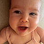 baby, beige, bright_eyes, child, chubby_cheeks, close_up, curious, cute, face, happy, indoor, infant, joyful, lying_down, peach_outfit, portrait, skin, sleeveless, smiling, texture