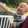 Kasen is registered to the contest to win money with this photo: backyard, chair, child, daylight, deck, happy, laughing, outdoor, parked_car, pointing, porch, portrait, short_sleeves, smiling, t_shirt, toddler, toy, trees, white_railing, yellow_toy