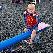 Kasen is registered to the contest to win money with this photo: baby, barefoot, blue_equipment, child, climber, daylight, face, grass, gripping, outdoor, park, playground, playground_equipment, portrait, red_shirt, rubber_surface, shorts, sitting, slide, spring_rider