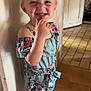 blonde_hair, child, cute, door, dress, floor, floral_pattern, happy, holding, indoor, light, person, playful, sandals, shadow, smiling, standing, tiled_floor, wall, young_child