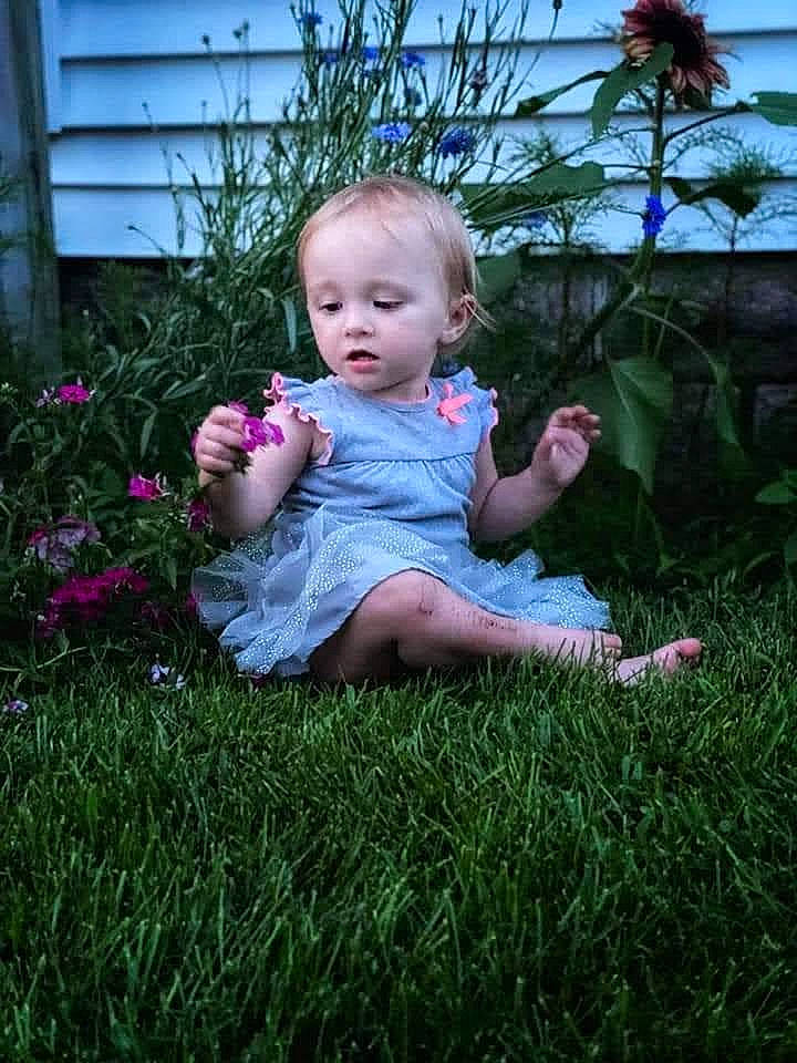 Brooke is registered to the contest to win money with this photo: baby, baby_toddler_clothing, botany, child, flower, flowerpot, fun, garden, grass, grass_family, grassland, happy, lawn, meadow, people_in_nature, person, petal, pink, plant, sitting