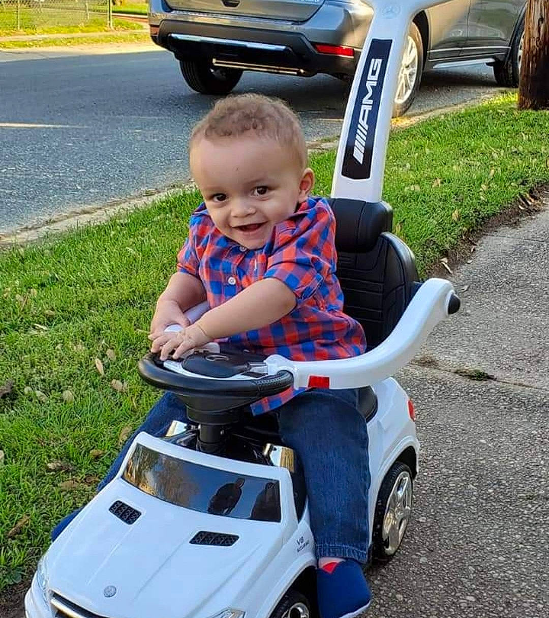Jaxon is registered to the contest to win money with this photo: automotive_design, automotive_exterior, automotive_lighting, automotive_tire, automotive_wheel_system, bumper, car, fender, grass, hood, joy, motor_vehicle, person, shorts, smile, tire, toddler, toy, vehicle, vehicle_registration_plate