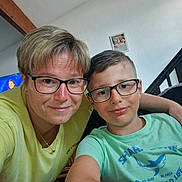 Thiméo a rejoint le concours — aidez-le/la à gagner de superbes lots ! child, adult, glasses, selfie, indoor, family, portrait, smile, tshirt, short_hair, staircase, picture_frame, wall, television, casual, arm, table, living_room, necklace, people