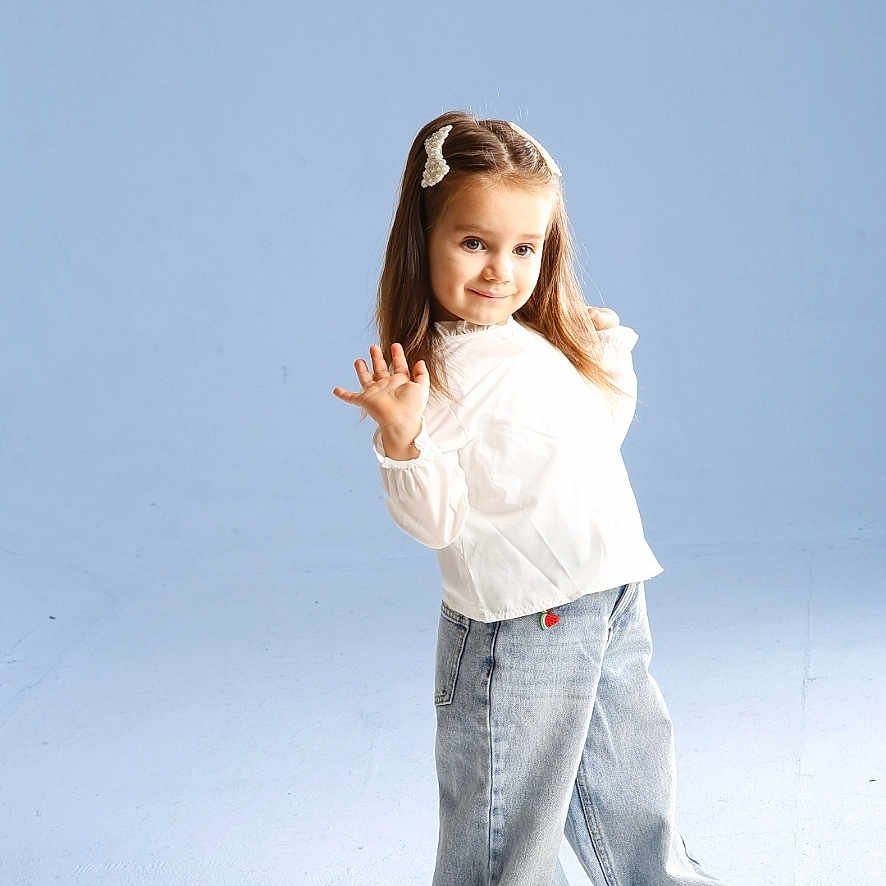 Sofia is registered to the contest to win money with this photo: blue_background, casual_clothing, child, cute, fashion, footwear, full_body, girl, hair_clip, happy, innocent, jeans, playful, portrait, posing, smiling, standing, studio, white_blouse, young