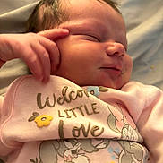 Adeline is registered to the contest to win money with this photo: newborn, baby, sleeping, infant, pink_clothing, floral_design, cute, peaceful, portrait, closeup, hand, face, skin, soft, child, indoors, text_on_clothing, adorable, young, resting