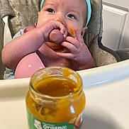 Emilia is registered to the contest to win money with this photo: baby, high_chair, baby_food, butternut_squash, messy, face, headband, blue, kitchen, food_jar, feeding, child, infant, pink_bib, hands, smearing, container, cabinet, organic, toddler