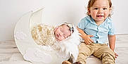 Emilia is registered to the contest to win money with this photo: baby, blanket, blue_shirt, brown_shoes, child, clothing, cradle, crescent_moon, cute, floor, fur, headband, indoor, pants, portrait, sleeping, smiling, toddler, white_wall, wooden_floor
