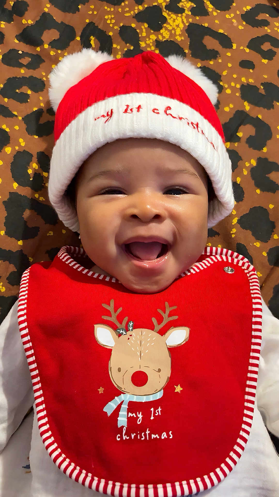 Chimamanda joined the competition — help win amazing prizes! baby, smiling, red_hat, christmas_bib, reindeer, holiday, infant, cute, happy, leopard_print, patterned_background, festive, portrait, face, headwear, clothing, holiday_season, child, cheerful, indoor