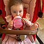 baby, child, sippy_cup, car_seat, pink, red, foot, hand, face, eyes, clothing, seatbelt, infant, cute, indoors, person, portrait, holding, drinking, comfortable