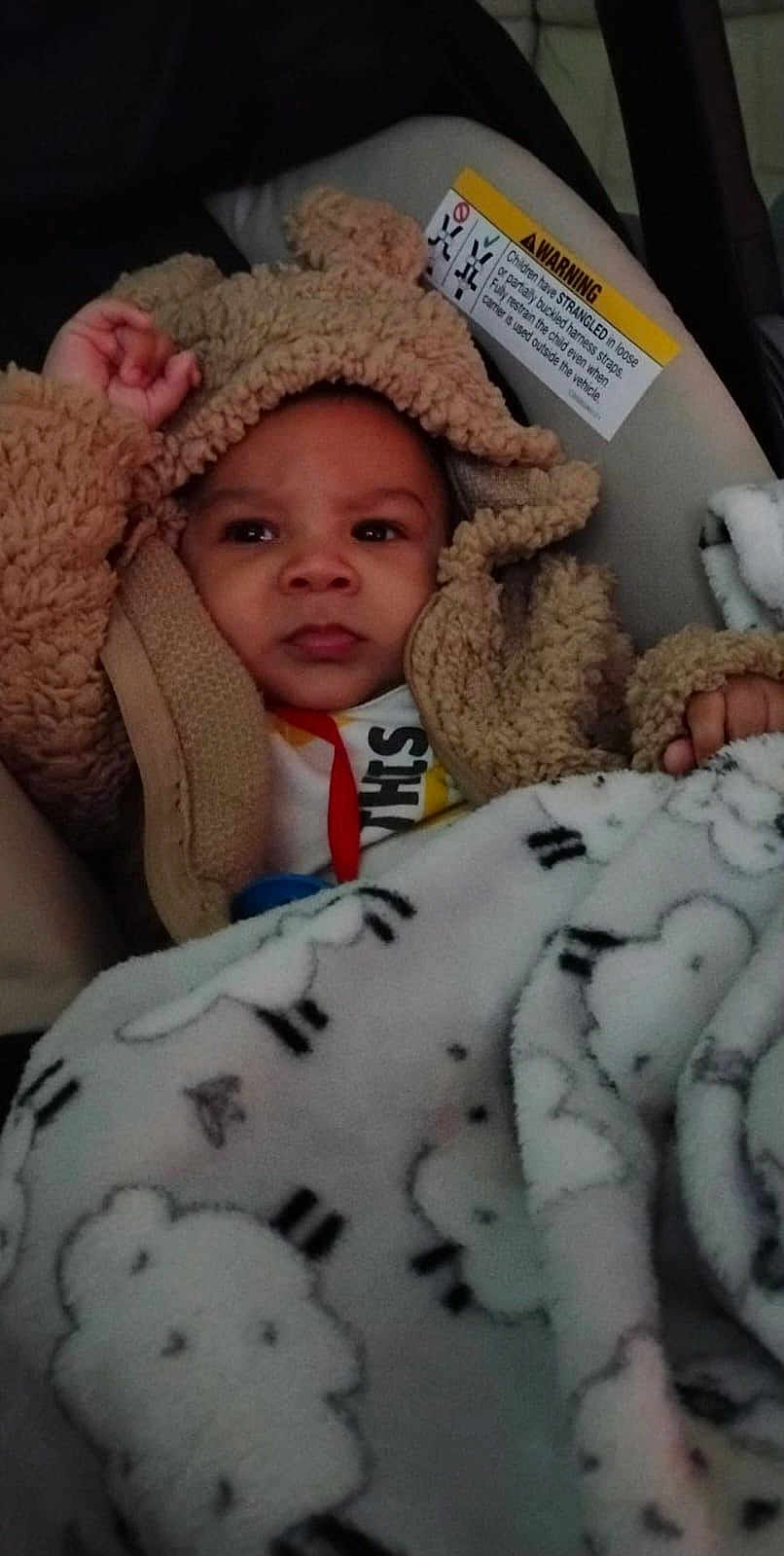 Yeremiah is registered to the contest to win money with this photo: baby, blanket, car_seat, child, close_up, cozy, eyes, fabric, face, fuzzy, hand, hooded_jacket, infant, pacifier_clip, pattern, portrait, seat, sleepy, strap, warning_label