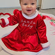 Elynn a rejoint le concours — aidez-le/la à gagner de superbes lots ! baby, child, smile, red_dress, santa_baby, heart_toy, blanket, indoor, happy, cute, holiday, festive, sitting, white_socks, floor, face, young_child, person, portrait, cozy