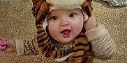 Chloe is registered to the contest to win money with this photo: toddler, child, tiger_hat, leopard_print, carpet, indoor, smiling, happy, cute, baby, dress, floor, toy, laundry_basket, blanket, home, person, headwear, playful, infant