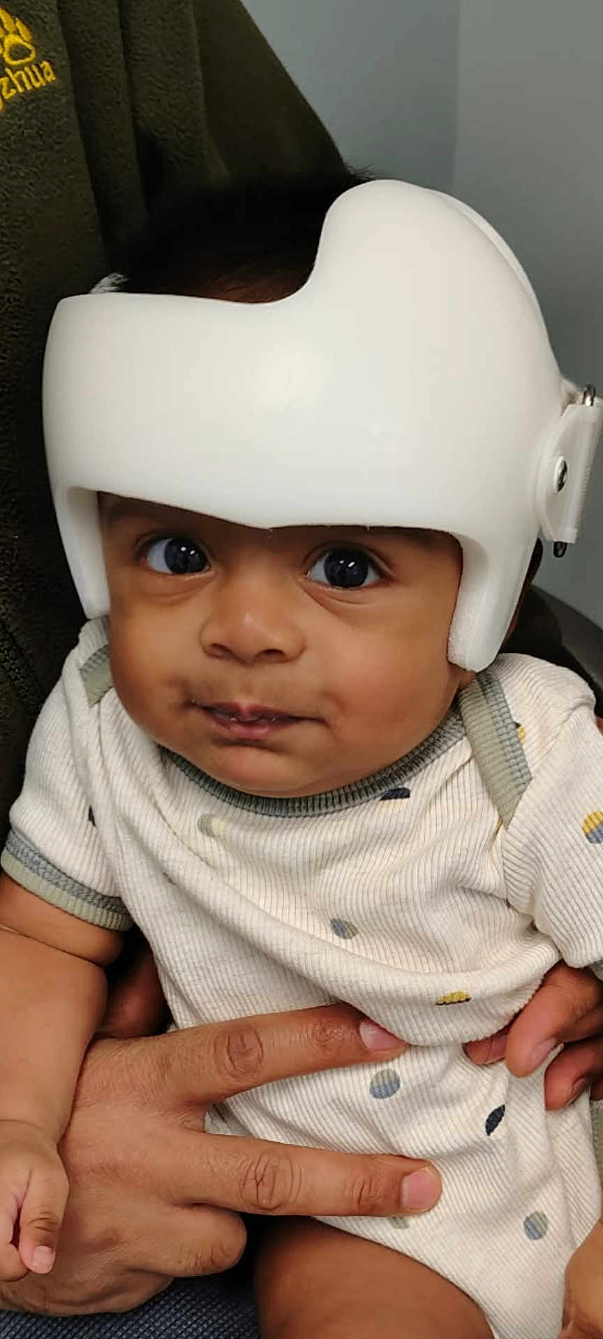 Anvay is registered to the contest to win money with this photo: baby, infant, helmet, protective_gear, hand, clothing, person, face, eyes, cute, child, indoor, portrait, skin, expression, sitting, apparel, support, young, headgear