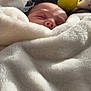 baby, sleeping, blanket, cozy, soft, plush_toy, yellow_moon, indoor, peaceful, infant, face, closeup, comfort, warm, nap, child, cushion, fabric, light, shadow