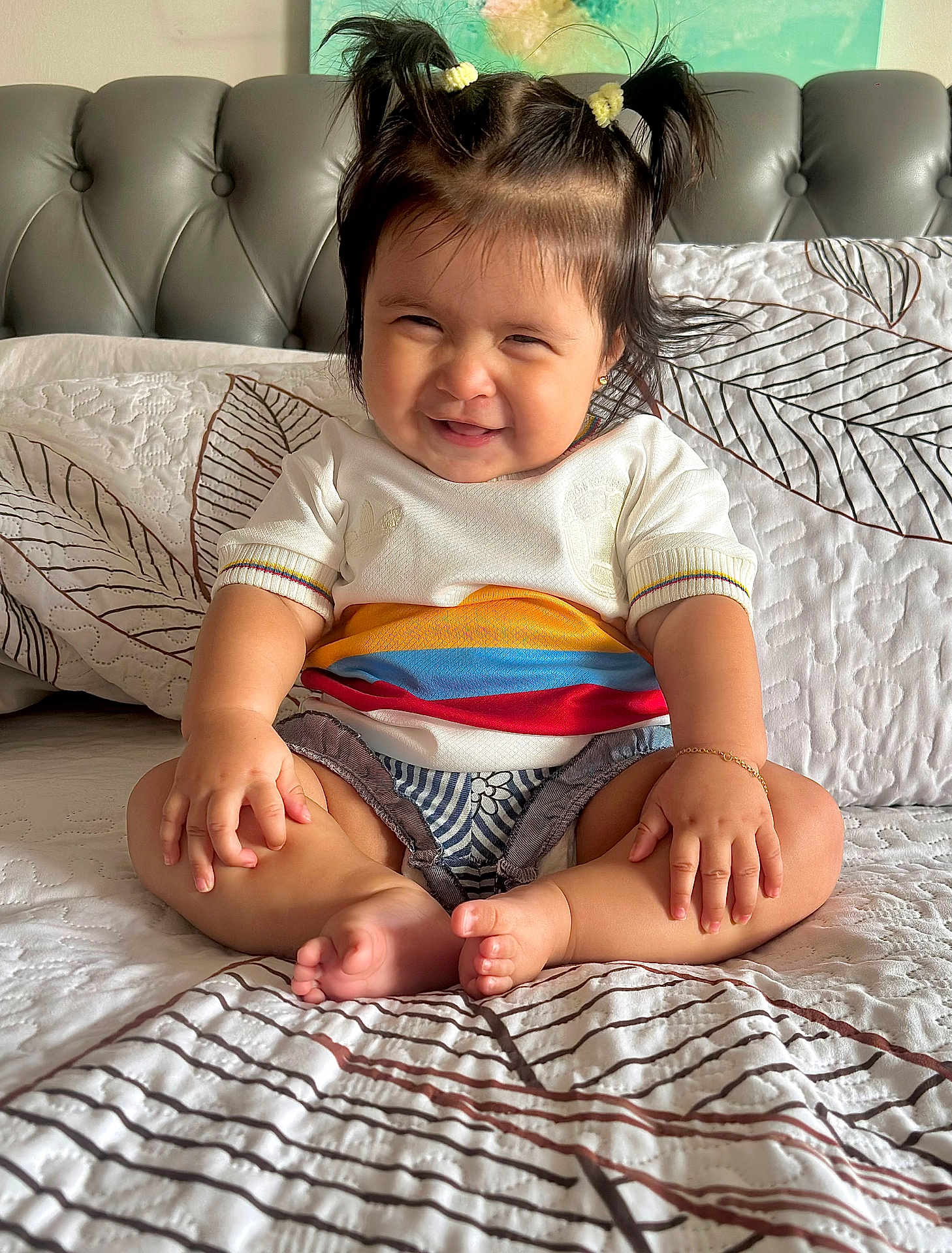 Zoe is registered to the contest to win money with this photo: baby, child, smiling, pigtails, sitting, bed, bedspread, pattern, clothing, bracelet, indoors, happy, cute, portrait, person, skin, hair, foot, hand, furniture