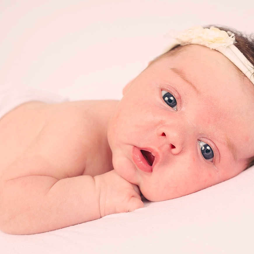 Issabella Rose is registered to the contest to win money with this photo: arm, baby, child, closeup, cute, expression, face, flower, headband, human, infant, lying_down, newborn, peaceful, pink, portrait, resting, skin, soft_light, white_background